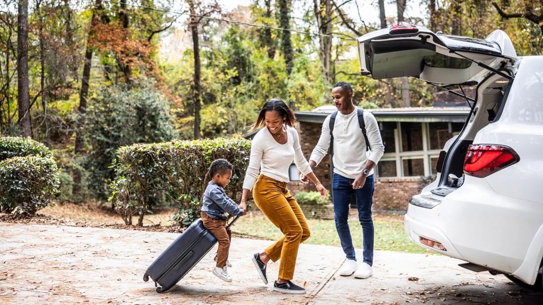 Happy family packing luggage into vehicle for a trip