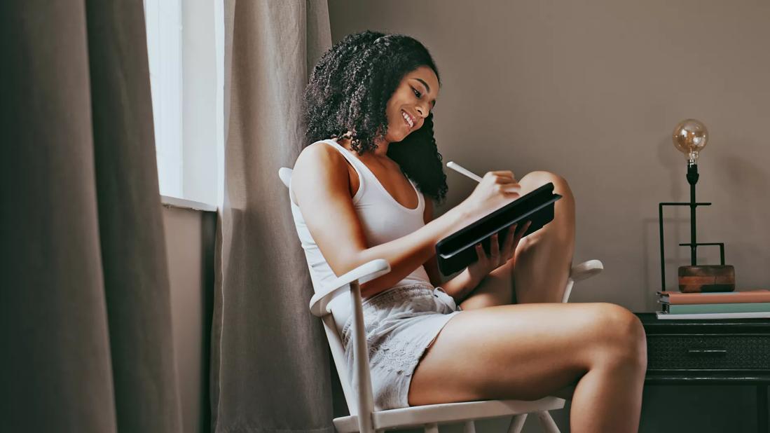 Person sitting in chair writing in tablet