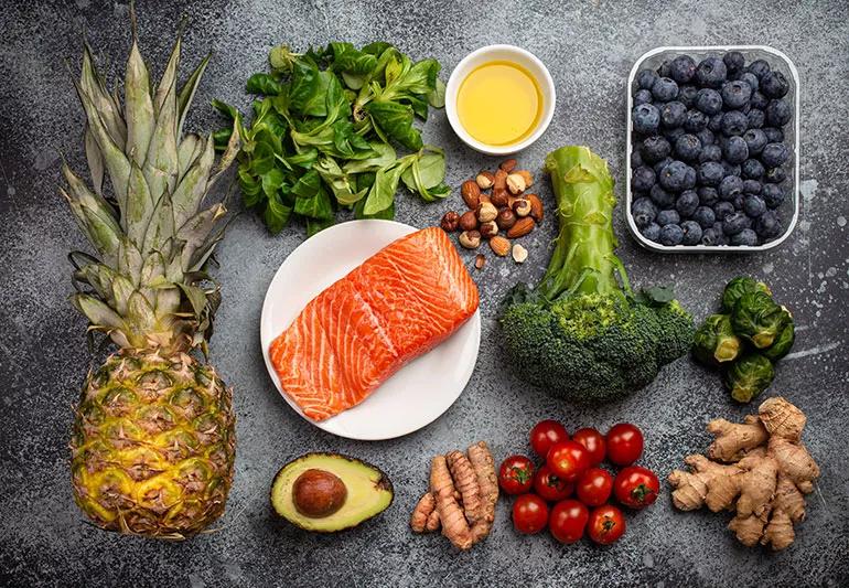 Counter full of heal;thy foods, including salmon, avocado, ginger, fruit, greens and nuts