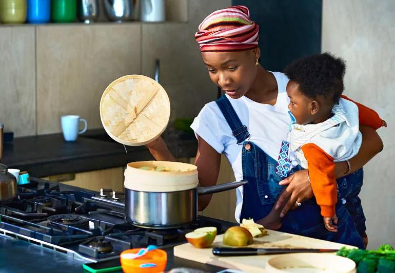 Woman cooking while holding infant son