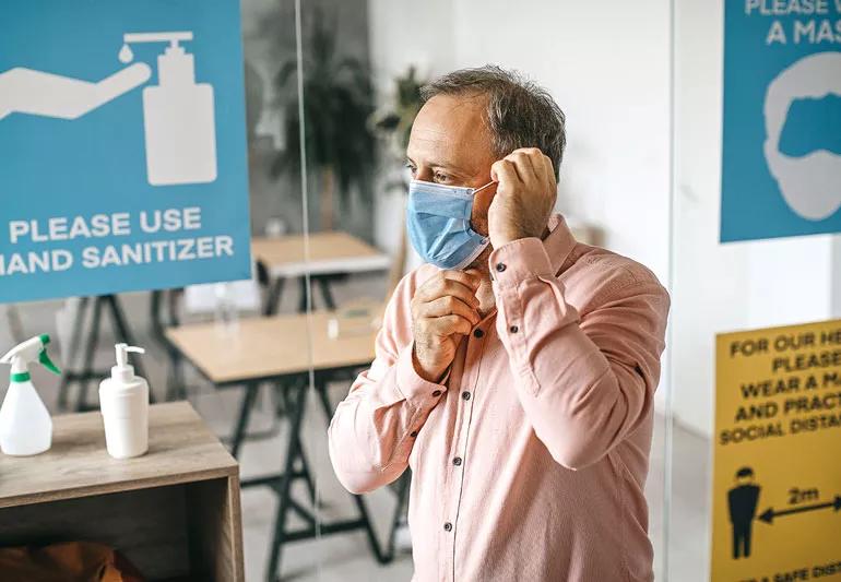 man putting on his covid mask after washing his hands