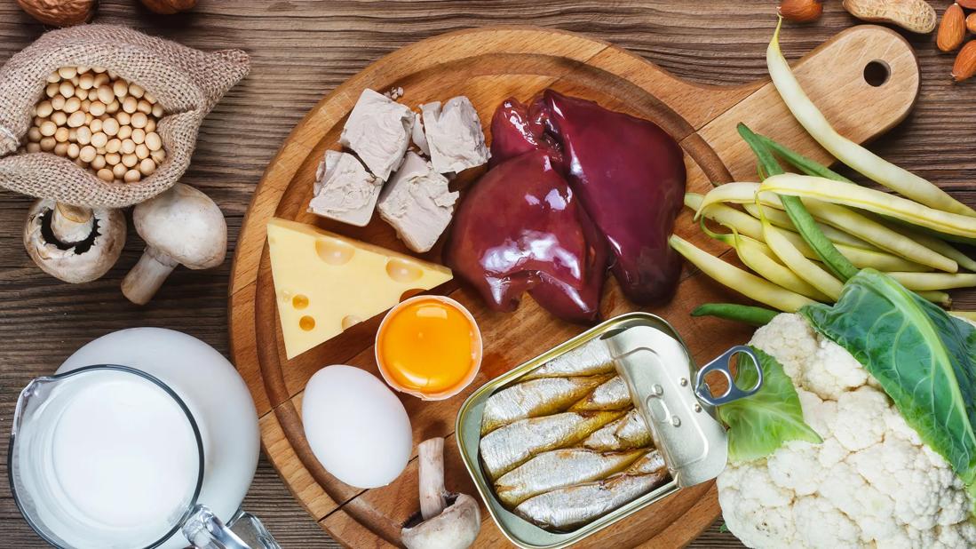 Biotin-rich foods, like liver, sardines, mushrooms and cheese, on wooden serving tray