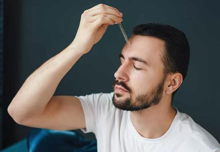 Person applying facial oil to forehead.