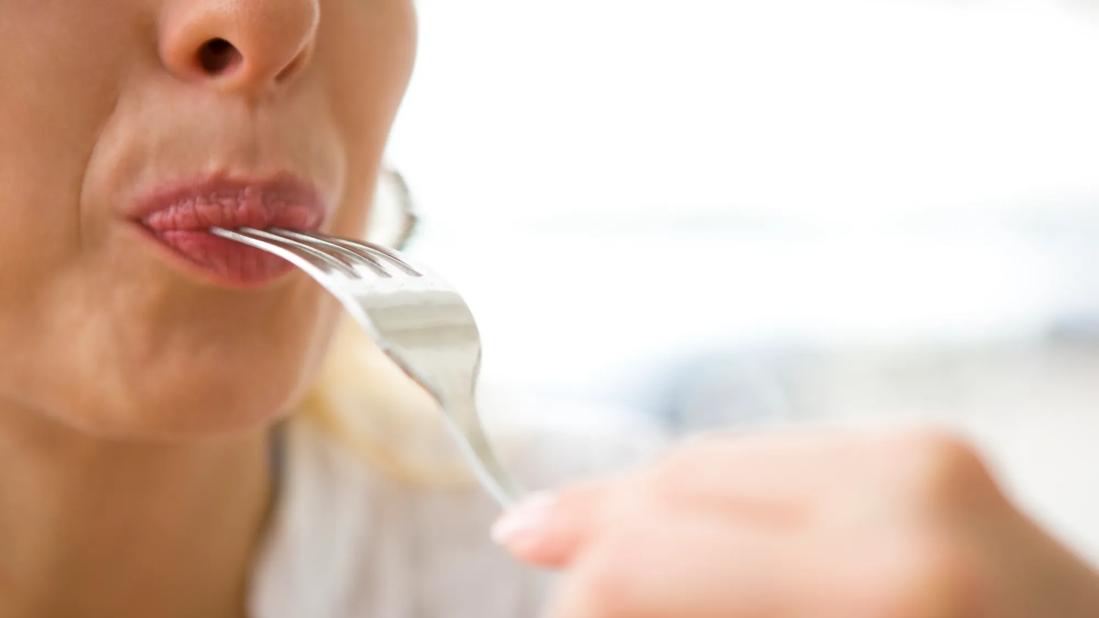 Person taking a bite, with fork in their mouth