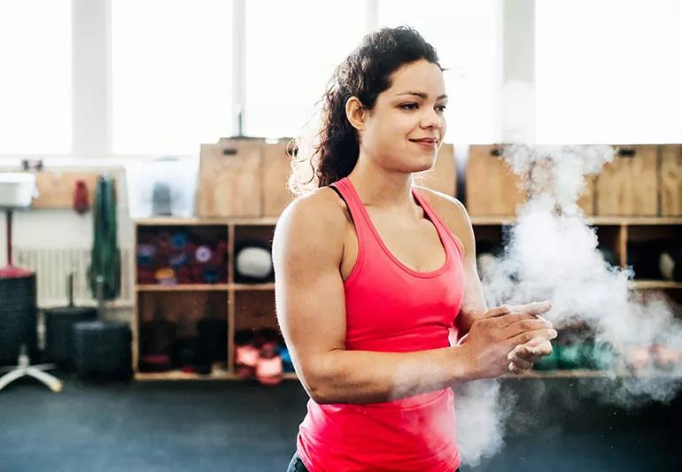 A gymnast puts chalk on their hands.