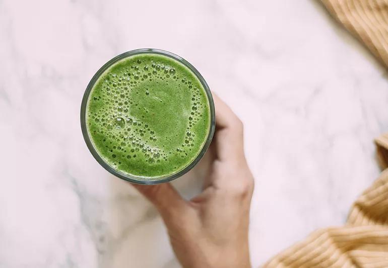 A green smoothie with strawberries in it.