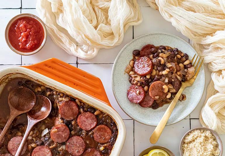 A bowl and pan of multicolored baked beans made with coins of low-fat kielbasa