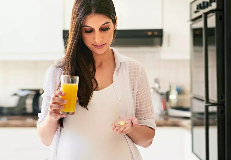 Woman taking vitamins with orange juice in morning
