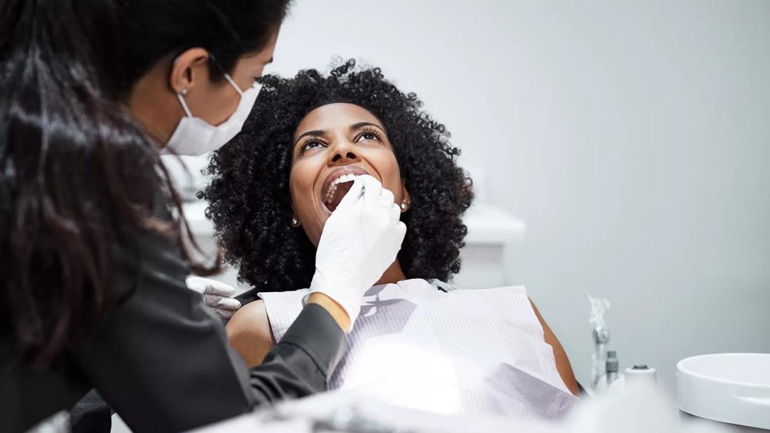 Person in dentist chair getting an exam by a dental provider