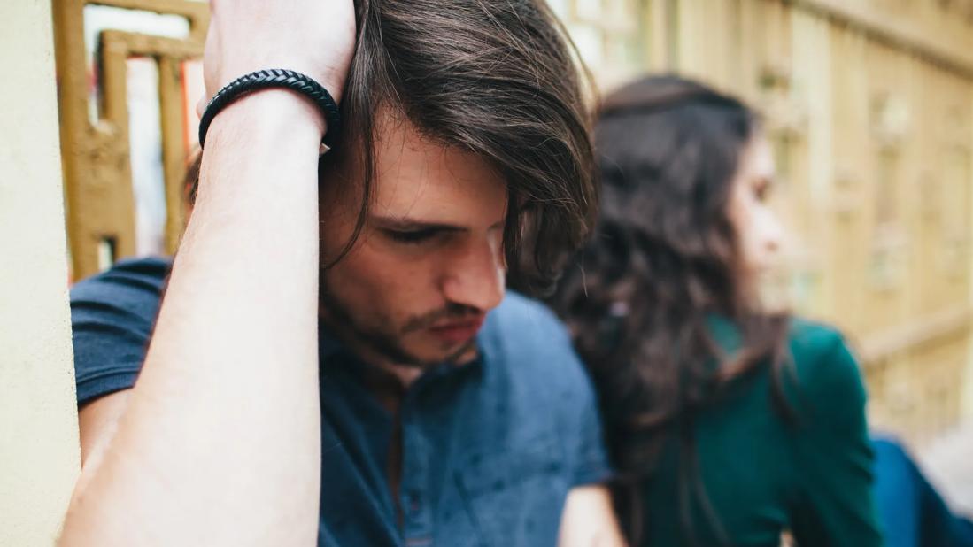 A couple sitting together, looking sad/distressed