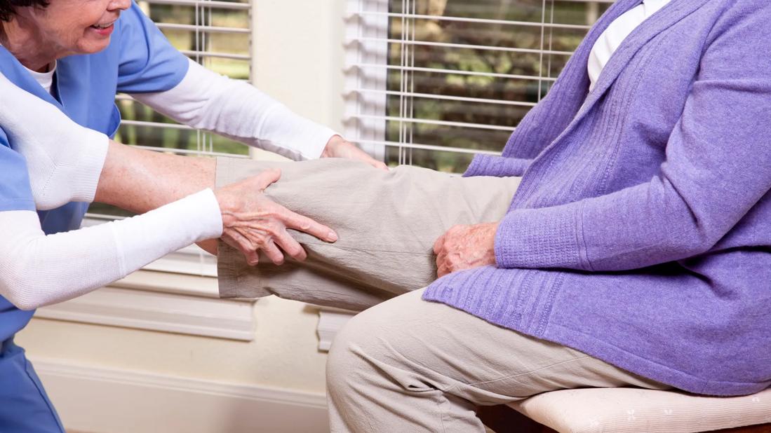 Home health worker examining knee of patient