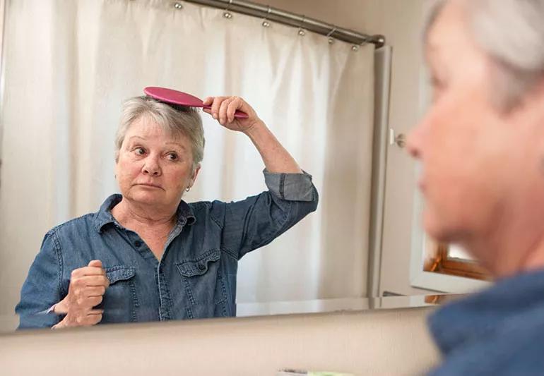 woman with grey hair looking in mirror