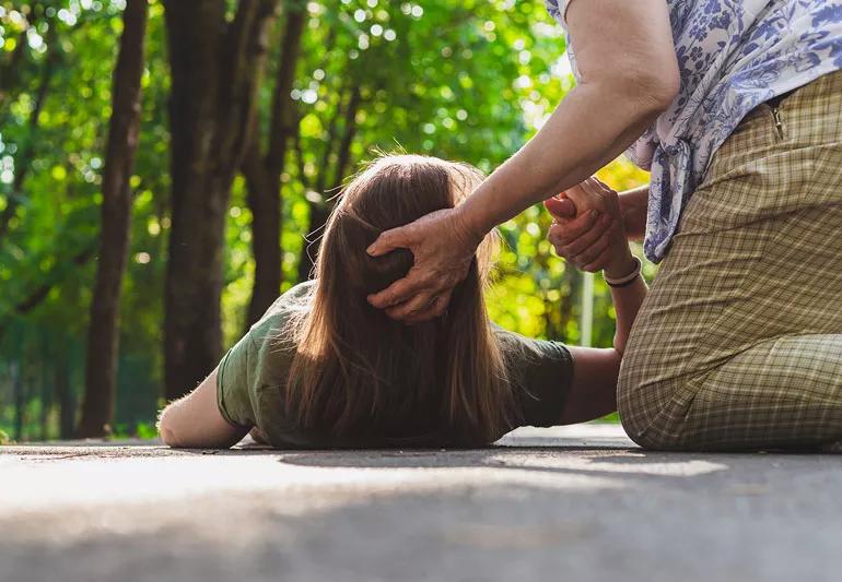 A person catching another person having a fainting spell.