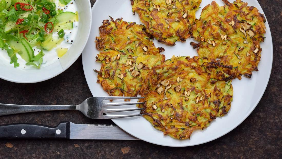 Plated walnut, zucchini and potato pancakes, with greens and apple side salad