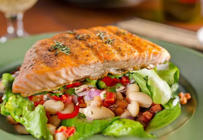 Closeup of grilled salmon and warm cannellini bean salad on a plate.