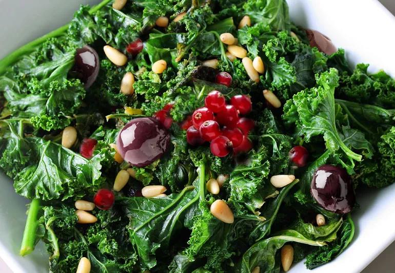 A plate of kale salad with currents, nuts and olives