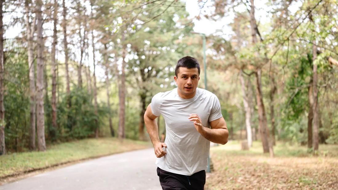 Man jogging/running on concrete path in park