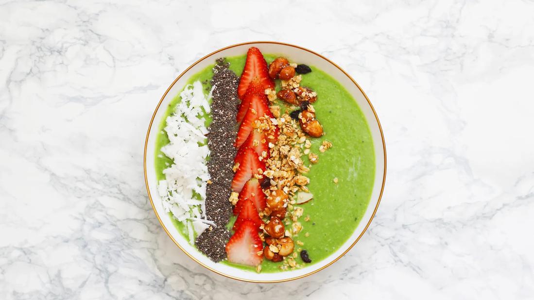 Green smoothie bowl with strawberries, granola, seeds and coconut