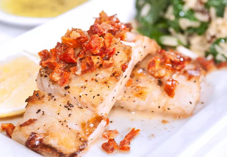 Sea bass topped with cherry tomatoes, crushed red pepper and lemon