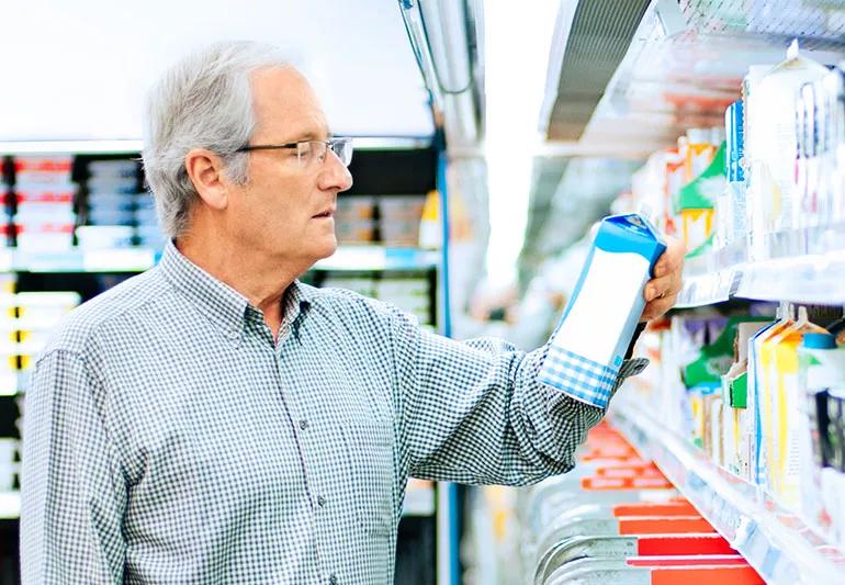 Elderly man checking food labels for sodium at grocery store