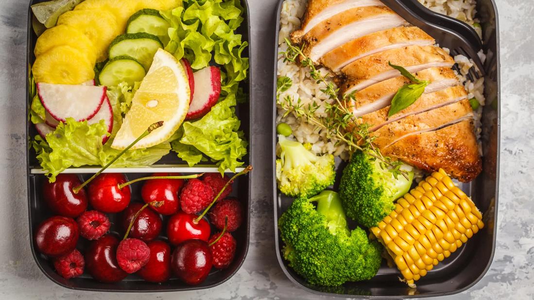 Meal trays of grilled chicken, grains, vegetables, and fruit