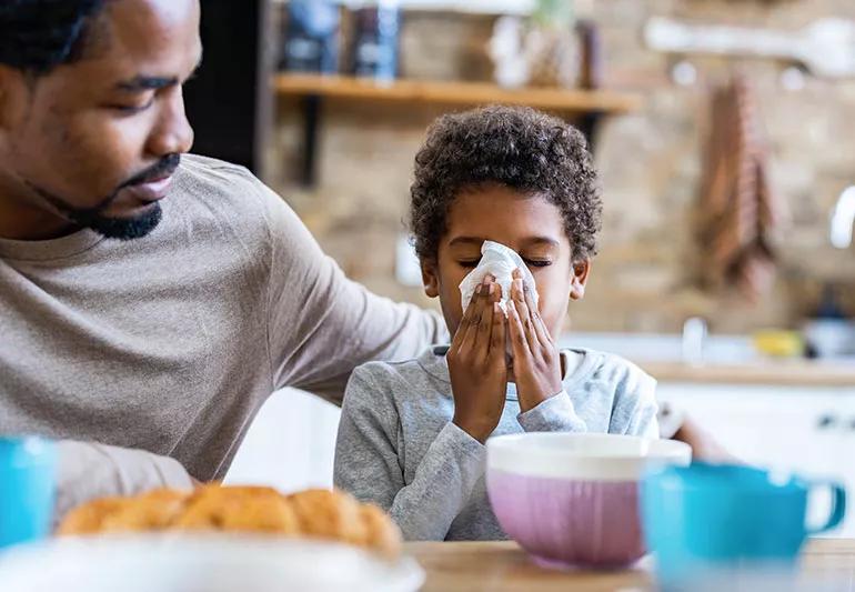 A parent consoles their child as they blow their nose.