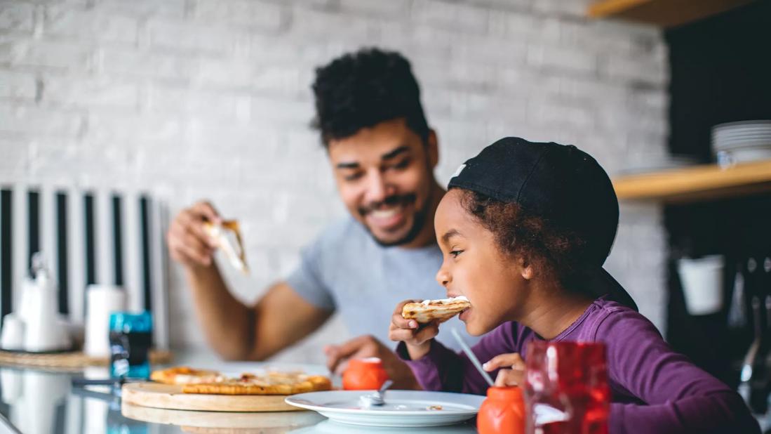 Caregiver and child eating pizza together