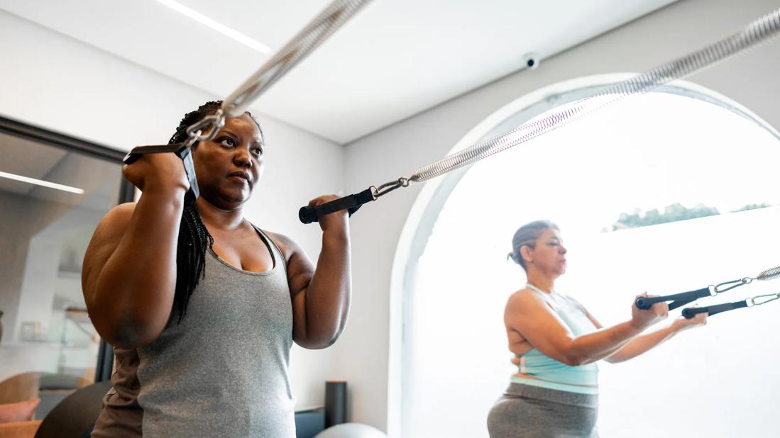 Two people using resistance bands at a gym