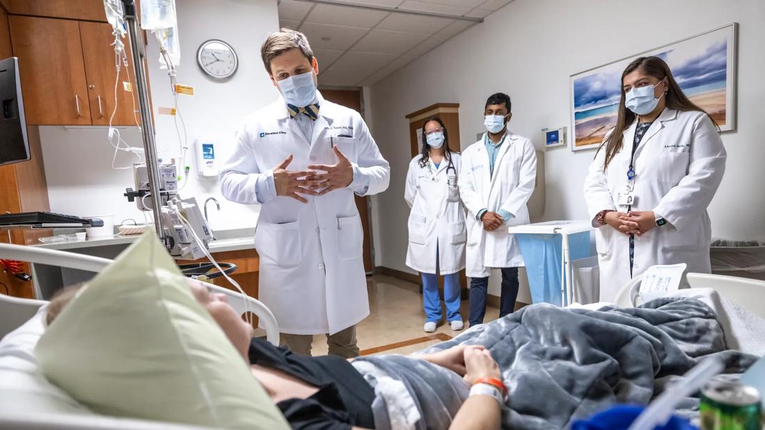 Doctor and team talking to patient in hospital bed