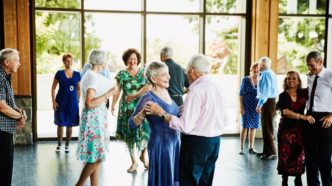 Smiling couple holding hands and finishing dance in community center