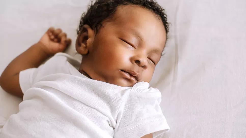 Baby in onesie asleep on back