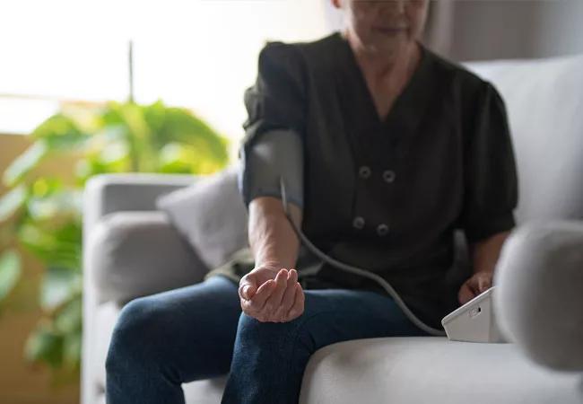 Woman checks blood pressure with home monitoring device