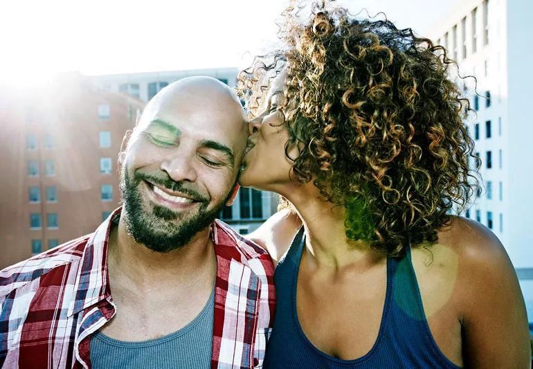 A woman kissing a man on the head.