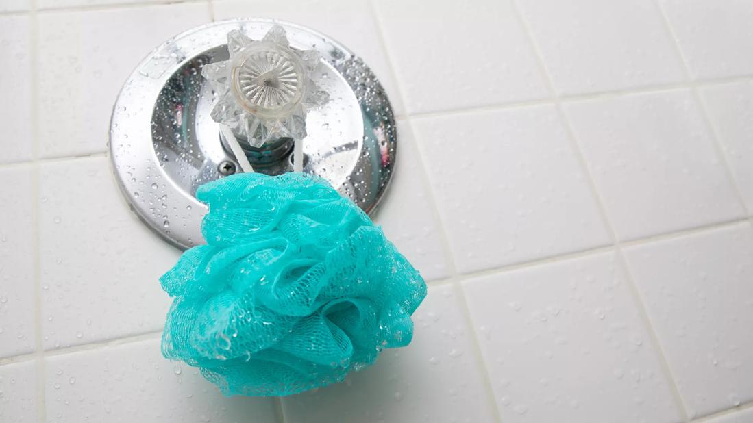 Wet plastic loofah hanging on shower knob