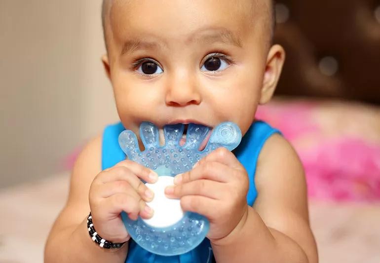 Closeup of a baby chewing on a teething toy.
