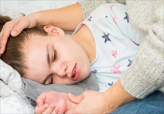 Child resting on bed with head on pillow.
