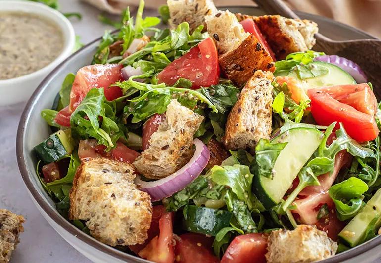 A bowl of Tuscan salad with croutons, red onion and tomatoes