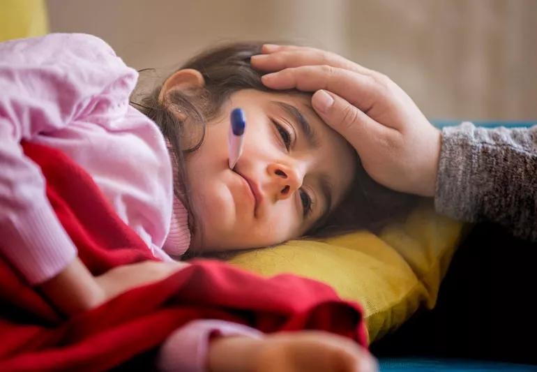 Sick child lying down with thermometer