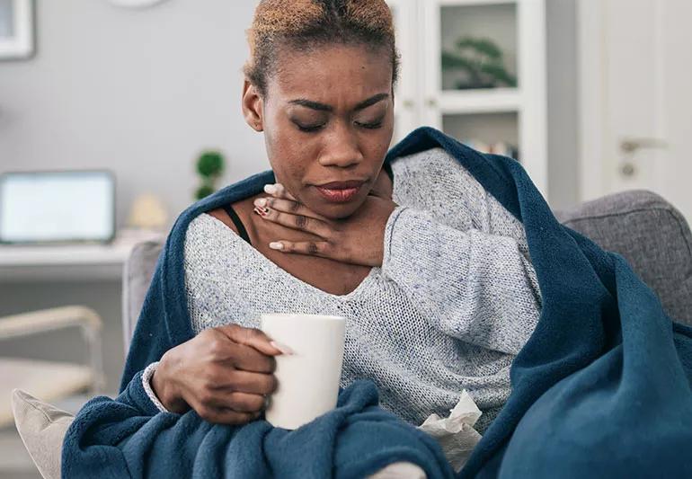 Woman with sore throat drinking hot beverage