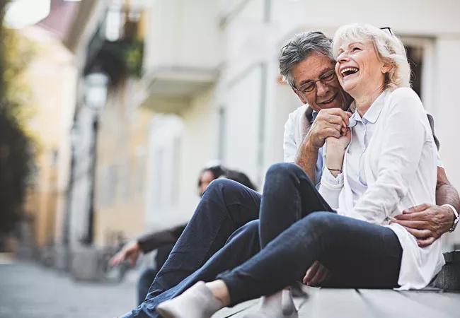 An elderly couple seated on a bench, enjoying each other's company.