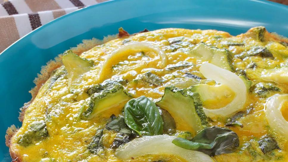 Closeup of a frittata with zucchini and onions on blue plate