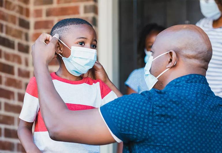 parent putting covid face mask on child