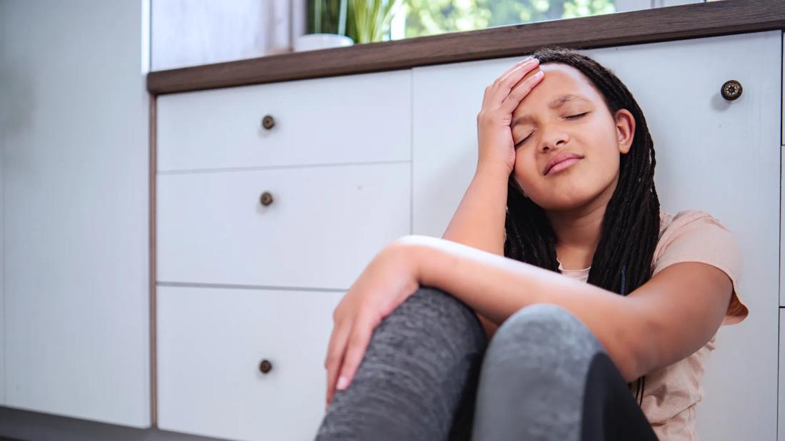 Girl sitting on floor with hand on her head