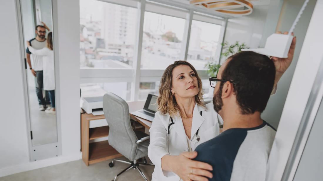 Healthcare provider measuring male's height in medical office