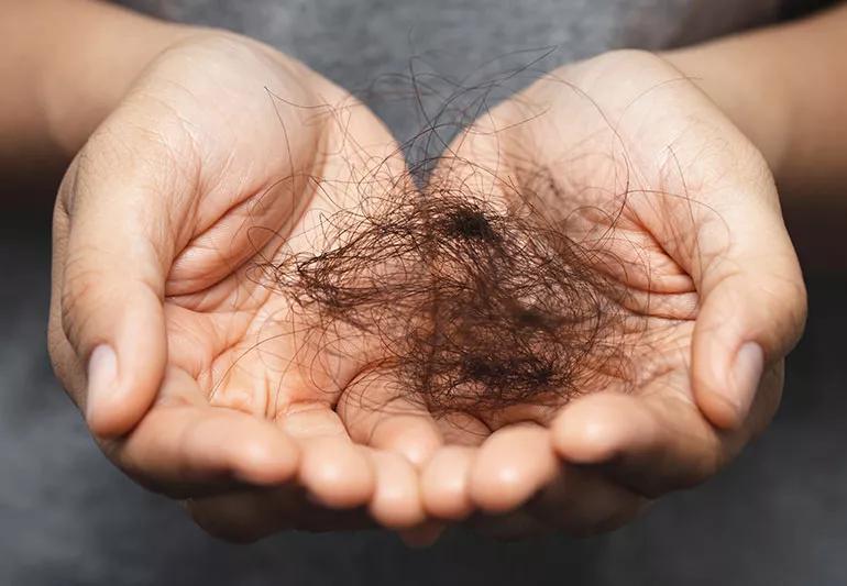 Close up of cupped hands holding a large clump of dark hair