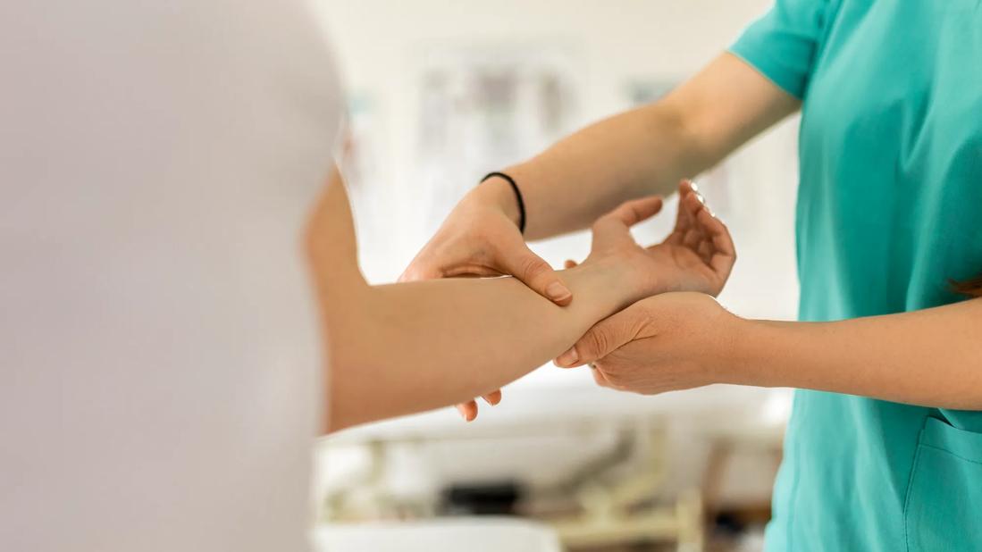 Healthcare provider examining a person's wrist and lower arm