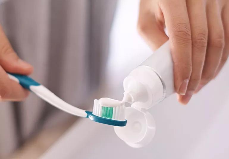 woman putting toothpaste on toothbrush