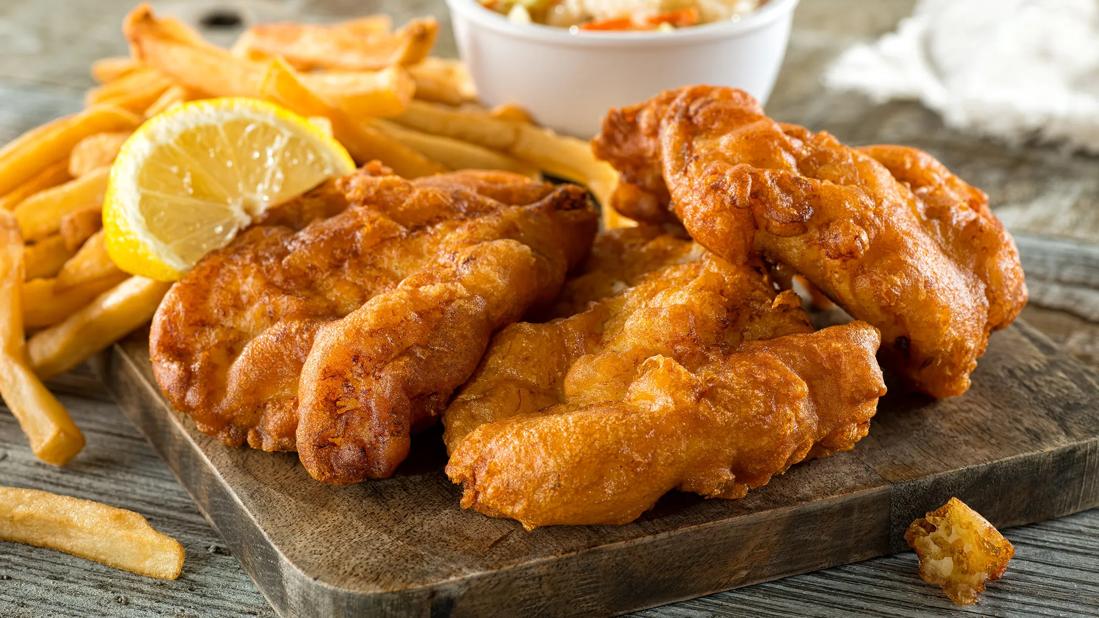 Wooden tray filled with fried fish, french fries and coleslaw