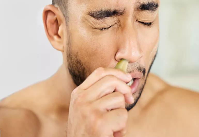 man putting garlic in nose