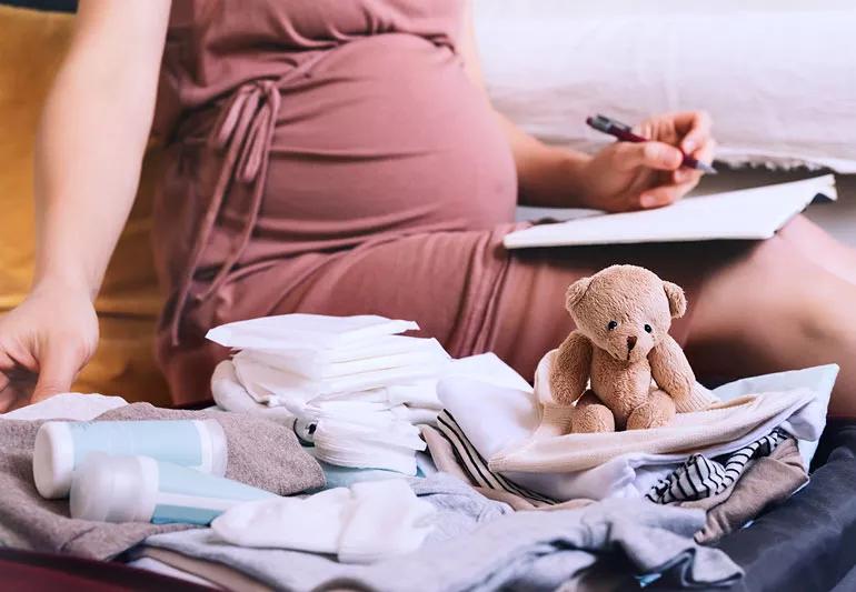 Pregnant person at home packing a hospital bag in preperation for birth.